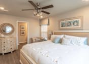 Thumbnail 7 of 9 - A bedroom with a large bed, a dresser, and a ceiling fan.