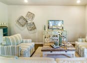 Thumbnail 8 of 9 - A living room with a striped couch and a coffee table with a vase on it.