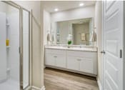 Thumbnail 9 of 9 - A bathroom with a white vanity and a walk-in shower.