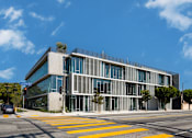 Thumbnail 2 of 9 - A modern building with a glass facade and a yellow crosswalk in front.