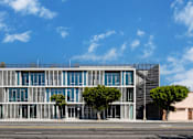 Thumbnail 5 of 9 - A modern building with a glass facade and trees in front.