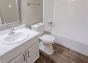 Thumbnail 13 of 34 - A white toilet sits next to a white sink in a bathroom.