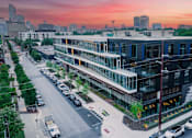 Thumbnail 11 of 16 - A modern building with a parking lot in front of it.