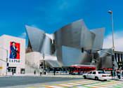 Thumbnail 16 of 18 - A modern building with a curved facade and a large poster of a man in a suit on the side of a building.