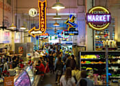 Thumbnail 15 of 18 - A busy market with a neon sign that says District Market.