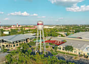 Thumbnail 12 of 19 - A water tower stands in front of a building complex.