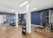 Thumbnail 22 of 23 - A gym with a variety of equipment including a treadmill, a bench press, and a squat rack.