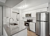 Thumbnail 9 of 23 - A modern kitchen with stainless steel appliances and white cabinetry.