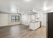 Thumbnail 5 of 23 - A spacious room with a kitchenette and a ceiling fan.