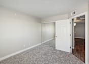 Thumbnail 13 of 23 - A room with a white door and carpeted floor.