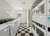 Thumbnail 21 of 23 - A laundromat with a checkered floor and rows of washers and dryers.