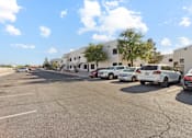 Thumbnail 23 of 23 - A parking lot with several cars parked in front of a building.