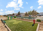 Thumbnail 20 of 23 - A playground with a green bench, a red fire hydrant, and a tennis court.