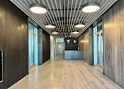 Thumbnail 7 of 9 - A long hallway with wood floors and ceiling lights.
