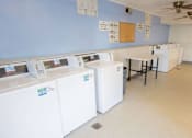 Thumbnail 14 of 34 - A room with washing machines and a table.