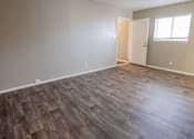 Thumbnail 8 of 34 - A room with wooden flooring and a doorway leading to another room.