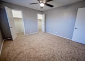 Thumbnail 22 of 34 - A room with a ceiling fan and carpeted floor.