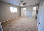Thumbnail 21 of 34 - A room with a ceiling fan and carpeted floor.