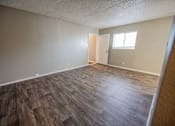 Thumbnail 29 of 34 - A room with wooden flooring and a door leading to another room.