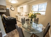 Thumbnail 20 of 34 - A kitchen with a black fridge and a glass table with chairs.