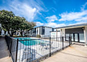 Thumbnail 28 of 34 - A pool surrounded by a black fence with a building in the background.
