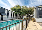 Thumbnail 31 of 34 - A pool is surrounded by a fence and a walkway.