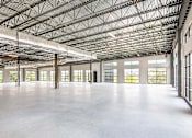 Thumbnail 10 of 19 - A large, empty warehouse with a high ceiling and large windows.