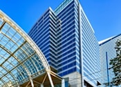 Thumbnail 10 of 10 - A modern glass building with a curved glass entrance.