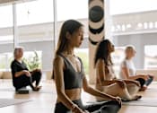 Thumbnail 7 of 18 - A group of people are sitting on yoga mats in a room.