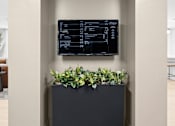 Thumbnail 4 of 25 - A black planter box with green plants sits on a grey floor.