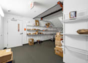 Thumbnail 19 of 25 - A storage room with white shelves and boxes on the floor.