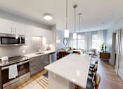 Thumbnail 2 of 30 - A modern kitchen with a white marble island and stainless steel appliances.