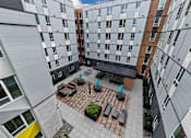 Thumbnail 23 of 38 - A courtyard with a table and chairs surrounded by buildings.