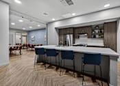 Thumbnail 19 of 38 - A modern kitchen with a long white island and blue chairs.