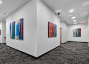 Thumbnail 16 of 38 - A hallway with a series of paintings on the wall.