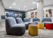 Thumbnail 2 of 38 - A modern waiting area with grey and yellow chairs and ottomans.