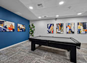 Thumbnail 5 of 38 - A pool table in a room with blue walls and abstract paintings on the wall.