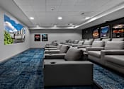 Thumbnail 25 of 38 - A row of grey sofas are lined up in a room with a blue carpet.