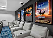 Thumbnail 6 of 38 - A row of white couches are lined up in a room with posters on the wall.