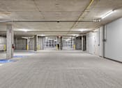 Thumbnail 28 of 38 - A large, empty parking garage with a concrete floor and walls.