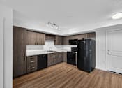 Thumbnail 26 of 38 - A modern kitchen with dark wood cabinets and a black refrigerator.