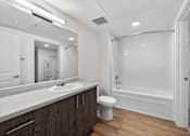 Thumbnail 10 of 38 - A modern bathroom with a white tub and wooden cabinets.