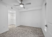 Thumbnail 11 of 38 - A room with a ceiling fan and carpeted floor.
