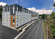 Thumbnail 38 of 38 - A modern multi-story building with a parking lot in front.