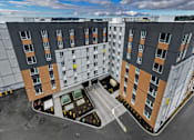 Thumbnail 33 of 38 - A modern apartment complex with a parking lot in front.