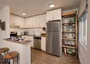 Thumbnail 20 of 51 - A modern kitchen with a stainless steel refrigerator and wooden bar stools.