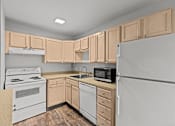Thumbnail 32 of 51 - A kitchen with a white refrigerator, white oven, and wooden cabinets.