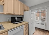 Thumbnail 19 of 51 - A kitchen with a black microwave, white fridge, and brown cabinets.