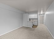 Thumbnail 35 of 51 - A white room with a kitchenette and a carpeted floor.
