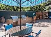 Thumbnail 11 of 51 - A table and chairs set up under a blue umbrella.